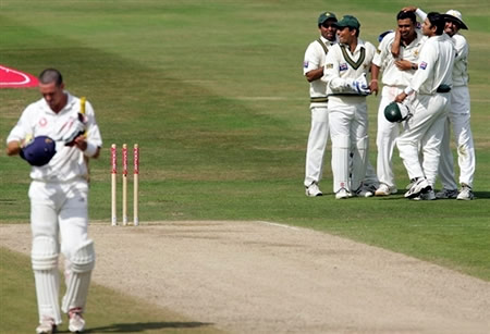 Kevin Pietersen walks back to the Pavilion as Pakistan players congratulate Danish Kaneria