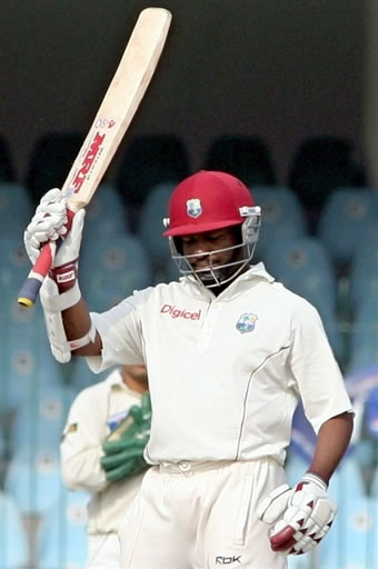 Lara raises his bat after his century