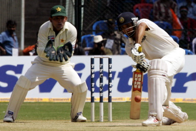 VVS Laxman hits a ball to the boundary as Kamran Akmal looks on