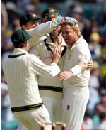 Australian bowler Shane Warne is congratulated after taking the wicket of Virender Sehwag