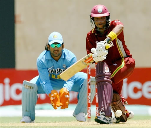 Sarwan slams a shot as Dhoni looks on